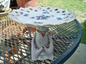 Thrift-shop vase and delicate plate repurposed into a consignment shop showcase riser